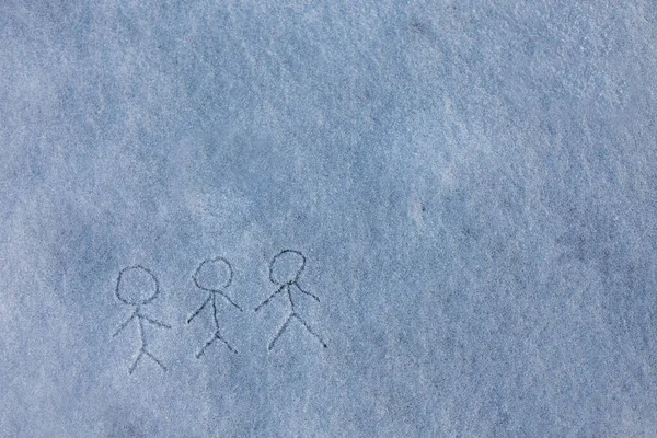 Painted by child three primitive little men holding hands. Picture on the snow. Happy winter season.