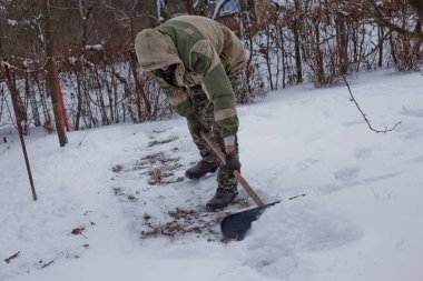man clears the yard of the snow With Shovel. Heavy snowfall in winter. High level of snow. Snowy snowdrift.