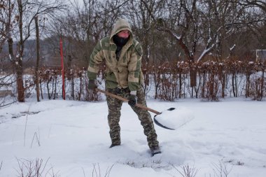 man clears the yard of the snow With Shovel. Heavy snowfall in winter. High level of snow. Snowy snowdrift.