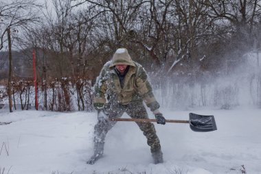 man clears the yard of the snow With Shovel. Heavy snowfall in winter. High level of snow. Snowy snowdrift.