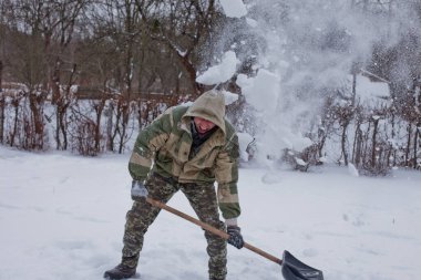 man clears the yard of the snow With Shovel. Heavy snowfall in winter. High level of snow. Snowy snowdrift.