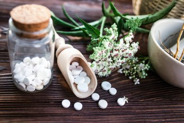 Valerian tablets with sedative properties. Pharmaceutical jar with pills on a wooden table. Cooking Valerian Root in a Mortar for Herbalism Elixirs. Soft focus