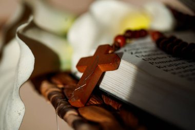 Yanında çiçekler olan bir İncil 'in üzerinde ahşap bir haç var. Sahne haçın ve İncil 'in yakın çekimini gösteriyor. Ayarlar basit ve inanç ve yansımaya odaklı..