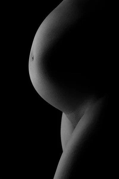 Belly of a pregnant woman on a dark background Stock Photo