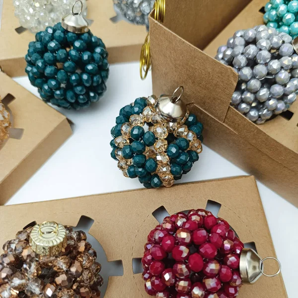 Farklı renklerde kristal boncuklardan yapılmış zarif el yapımı Noel topları koleksiyonu. Hediye kutularında gösterilen bayram süslemeleri. Lüks kış dekorasyonu konsepti