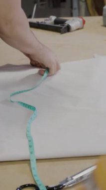 Bir çalışma masasını kesmek için kumaşı ölçen ve işaretleyen eller.
