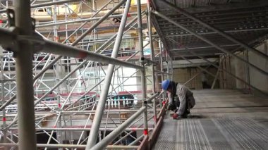 İnşaat işçileri yapı iskelesi üzerinde yoğun bir şekilde çalışıyorlar..