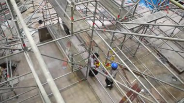 İki inşaat işçisi aktif yapı iskelesinde konuşuyor..