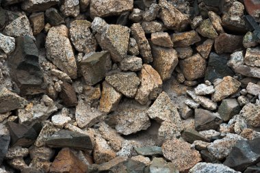 Karışık granit kayalara yakın çekim ve güneş ışığı altında ezilmiş taş dokusu..