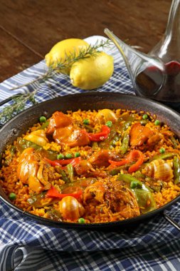 Valensiyalı Paella, klasik bir İspanyol yemeği, ahşap bir masada bir porron şarapla servis edilir.