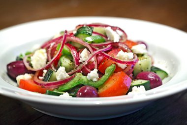 Kırmızı soğanlı salata, vişneli domates, zeytin ve keçi peyniri tabakta.