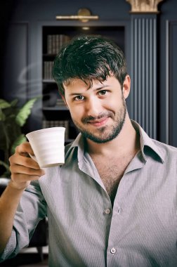 Genç yönetici kahvesini içerken gayri resmi poz veriyor.