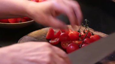 Bir aşçı, önde gelen bir tahta üzerinde domates keserken görülüyor..