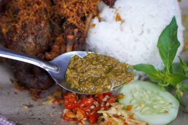 Kaldırım stili Madurese usulü kızarmış ördek. Kokulu baharatlar, beyaz pirinç, taze otlar, salatalık dilimleri ve hafif mango sambal ile servis ediliyor. Gıda görselleri için uygun, keskin bir aksan için.