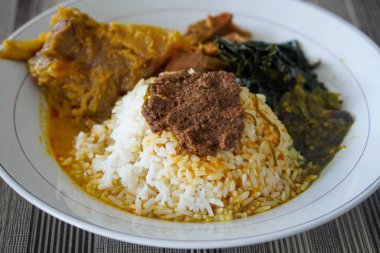 Padang bifteği tendon köri, sıcak pirinç, zengin hindistan cevizi sosu, taze tunjang parçaları, ve kalın Minang baharatları ile servis edilir doyurucu, lezzetli Endonezya yemeği atmosferi yaratır.