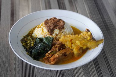 Padang bifteği tendon köri, sıcak pirinç, zengin hindistan cevizi sosu, taze tunjang parçaları, ve kalın Minang baharatları ile servis edilir doyurucu, lezzetli Endonezya yemeği atmosferi yaratır.