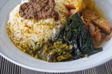 Padang bifteği tendon köri, sıcak pirinç, zengin hindistan cevizi sosu, taze tunjang parçaları, ve kalın Minang baharatları ile servis edilir doyurucu, lezzetli Endonezya yemeği atmosferi yaratır.