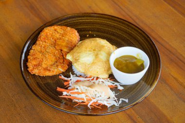 Buharda pişmiş pirinçli körili tavuk omleti, kızarmış tavuk pirzolası ve zengin Japon köri sosu, temiz kaplama sunumuyla modern kafein yemeğini rahatlatıyor.