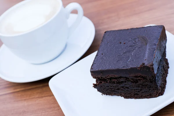 Chocolate brownie with a coffee in the background — Stock Photo, Image