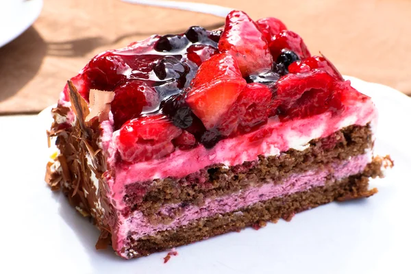 Delicious slice wild berry cake with different fruits and chocolate cream — Stock Photo, Image