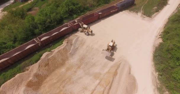 Train in motion, preparing for loading. Aerial Over Earth Moving Machines loading gravel on train. Two excavators at work — Stock Video