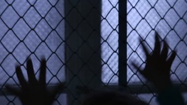 Mahkum Pov. Çaresiz çocuk sallayarak bir Metal çit kaçış için çalışıyor. Çocuk silüeti pencere çit eller. Mülteci veya terk edilmiş çocuk. Akıl hastanesi. Aile içi şiddet. Çit ve pencere parmaklar