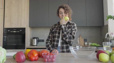 Modern Ev Mutfağı 'nda yemek pişirme fikirlerini araştırmak için cep telefonu kullanan bir kadın. Sağlıklı Yaşam Tarzı, Dijital Teknoloji, Çevrimiçi Tarifler, Mutfak İlhamları, Ev Yemekleri, Taze Malzemeler, Modern İçişleri