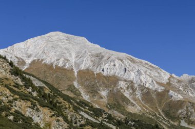 Bulgaristan 'ın Pirin Dağı' nın en yüksek mermer zirvesi olan Vihren Tepesi 'nin görkemli manzarası. Engebeli manzara, açık mavi sonbahar gökyüzü altında el değmemiş doğayı sergiliyor..