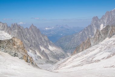 Keskin kayalık tepeler arasındaki buzul vadisi uzak sıradağlara doğru gidiyor.