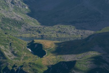 Dağ gölünün detaylı görüntüsü ve yeşil çimlerle çevrili patika.