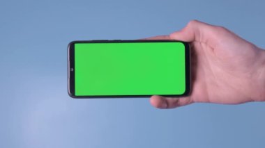 Adamın eli cep telefonunu yatay olarak yeşil ekran kroma anahtar akıllı telefon teknolojisi cep telefonu maviye.