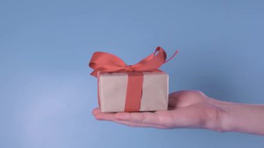 Bir hediye ile el mavi bir arka planda çerçeve girer