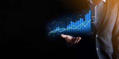 Holografik grafikler ve borsa istatistikleri tutan işadamı kâr elde ediyor. Büyüme planlama ve iş stratejisi kavramı. İyi ekonomi formunun dijital ekran görüntüsü