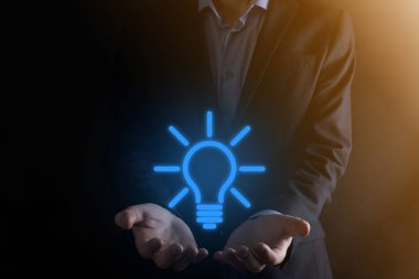 Elinde ampul olan takım elbiseli bir iş adamı. Elinde parlak bir fikir simgesi tutuyor. Metin için bir yer ile.