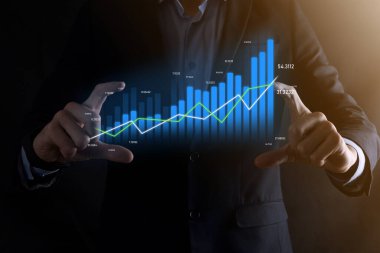 Holografik grafikler ve borsa istatistikleri tutan işadamı kâr elde ediyor. Büyüme planlama ve iş stratejisi kavramı. İyi ekonomi formunun dijital ekran görüntüsü