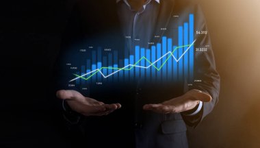 Holografik grafikler ve borsa istatistikleri tutan işadamı kâr elde ediyor. Büyüme planlama ve iş stratejisi kavramı. İyi ekonomi formunun dijital ekran görüntüsü
