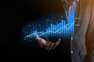 Holografik grafikler ve borsa istatistikleri tutan işadamı kâr elde ediyor. Büyüme planlama ve iş stratejisi kavramı. İyi ekonomi formunun dijital ekran görüntüsü