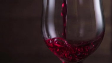 Koyu arkaplanda kırmızı şarap sallıyor. Şarap reklamı için çok güzel görüntüler. Yavaş Hareket .