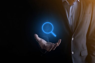 İş adamı ve adam el ele tutuşup cam ikonunu büyütüyorlar. İş dünyası, teknoloji ve internet kavramı