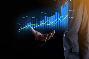 Holografik grafikler ve borsa istatistikleri tutan işadamı kâr elde ediyor. Büyüme planlama ve iş stratejisi kavramı. İyi ekonomi formunun dijital ekran görüntüsü