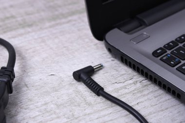 Laptop, bilgisayar duvarın yanındaki bir masada 220 voltluk bir prizden şarj oluyor. Enerji, birikim