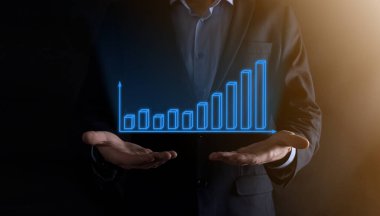 Holografik grafikler ve borsa istatistikleri tutan işadamı kâr elde ediyor. Büyüme planlama ve iş stratejisi kavramı. İyi ekonomi formunun dijital ekran görüntüsü