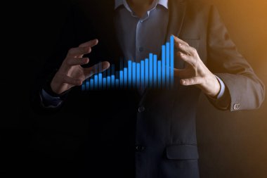 Holografik grafikler ve borsa istatistikleri tutan işadamı kâr elde ediyor. Büyüme planlama ve iş stratejisi kavramı. İyi ekonomi formunun dijital ekran görüntüsü