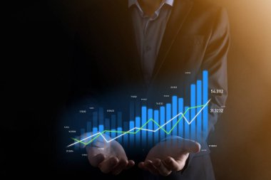 Holografik grafikler ve borsa istatistikleri tutan işadamı kâr elde ediyor. Büyüme planlama ve iş stratejisi kavramı. İyi ekonomi formunun dijital ekran görüntüsü