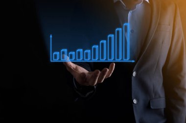 Holografik grafikler ve borsa istatistikleri tutan işadamı kâr elde ediyor. Büyüme planlama ve iş stratejisi kavramı. İyi ekonomi formunun dijital ekran görüntüsü