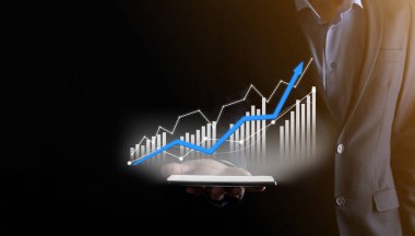 Holografik grafikler ve borsa istatistikleri tutan işadamı kâr elde ediyor. Büyüme planlama ve iş stratejisi kavramı. İyi ekonomi formunun dijital ekran görüntüsü
