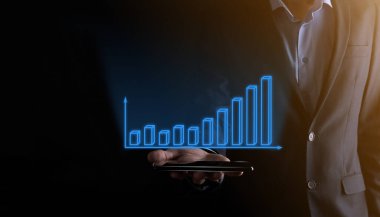 Holografik grafikler ve borsa istatistikleri tutan işadamı kâr elde ediyor. Büyüme planlama ve iş stratejisi kavramı. İyi ekonomi formunun dijital ekran görüntüsü