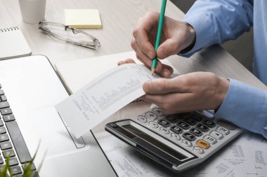 Hesap makinesi ve yazı makinesi kullanan bir adam ev ofisinin maliyet ve vergilerini hesaplayarak not alır. İşadamı iş yerinde evrak işleriyle uğraşıyor.