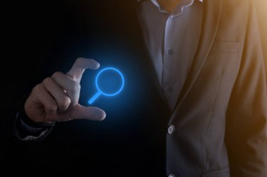 İş adamı ve adam el ele tutuşup cam ikonunu büyütüyorlar. İş dünyası, teknoloji ve internet kavramı