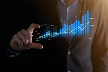 Akıllı telefon tutan ve holografik grafikler ve borsa istatistikleri gösteren bir işadamı kâr elde ediyor. Büyüme planlama ve iş stratejisi kavramı. İyi ekonomi formunun dijital ekran görüntüsü.